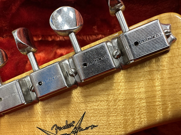 Close-up of vintage Kluson tuning machines on a Fender guitar headstock with signature on natural wood finish