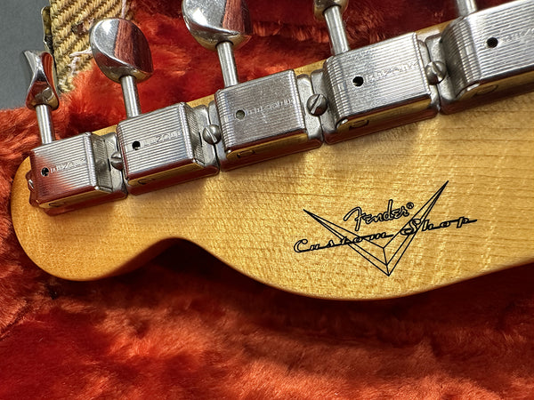 Close-up of Fender Custom Shop guitar headstock with vintage tuning pegs on orange plush lining