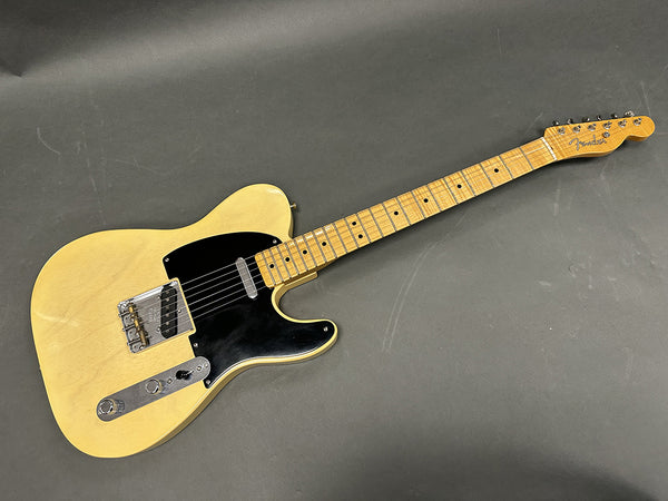 Vintage Fender Telecaster electric guitar with butterscotch blonde finish and black pickguard on gray background