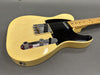 Vintage cream electric guitar with black pickguard and chrome control knobs on gray background