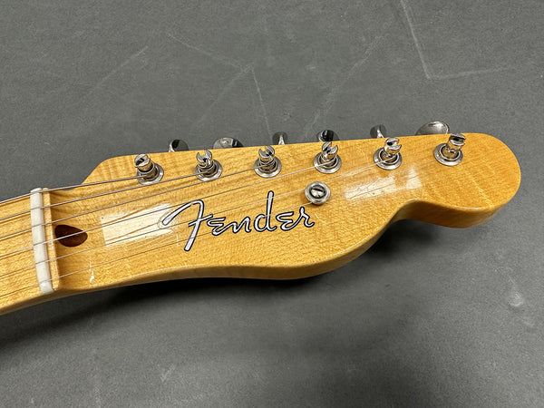 Close-up of Fender electric guitar headstock with tuning pegs on gray background