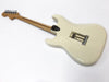 Back view of white electric guitar with maple neck and tremolo springs exposed on a white background