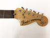 Close-up of Fender Stratocaster guitar headstock with six chrome tuning pegs and signature on natural wood finish