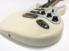 Close-up of white electric guitar body with chrome bridge, black tone and volume knobs, white pickguard, and input jack on white background