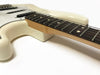 Close-up view of cream electric guitar body and maple neck with rosewood fretboard and dot inlays on white background