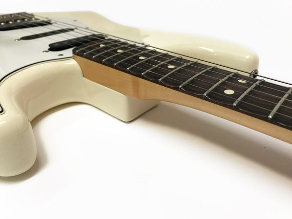 Close-up view of cream electric guitar body and maple neck with rosewood fretboard and dot inlays on white background
