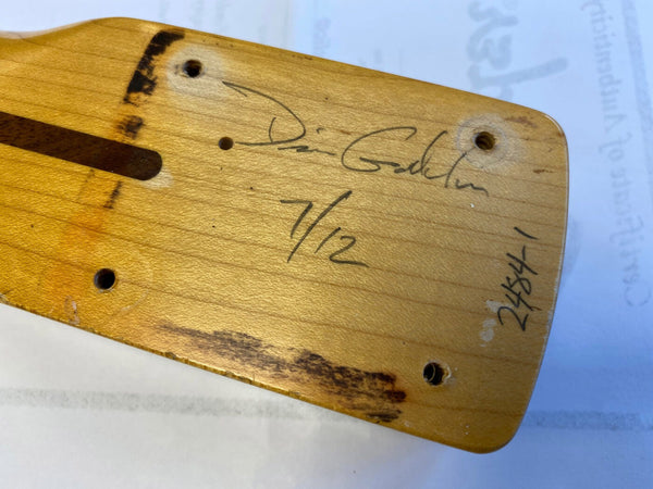 Close-up of a signed maple guitar neck heel with wear marks and a serial number written in black ink.