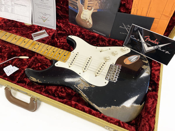 Fender Custom Shop black relic Stratocaster electric guitar with maple neck and white pickguard in vintage tweed hard case with red plush interior and Fender Custom Shop documentation.