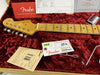 Fender Stratocaster guitar headstock and maple fretboard with metal tuning pegs in red plush-lined case, Fender Custom Shop certification and original tags including tremolo springs diagram and serial number tag.