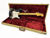Black Fender Stratocaster electric guitar with worn finish, maple neck, and white pickguard in tweed hard case with red plush interior lining