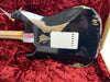 Worn black electric guitar body with visible wood patches and white backplate, resting in red velvet-lined guitar case