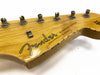 Close-up of vintage Fender Stratocaster guitar headstock with tuning pegs and string tree on natural wood finish