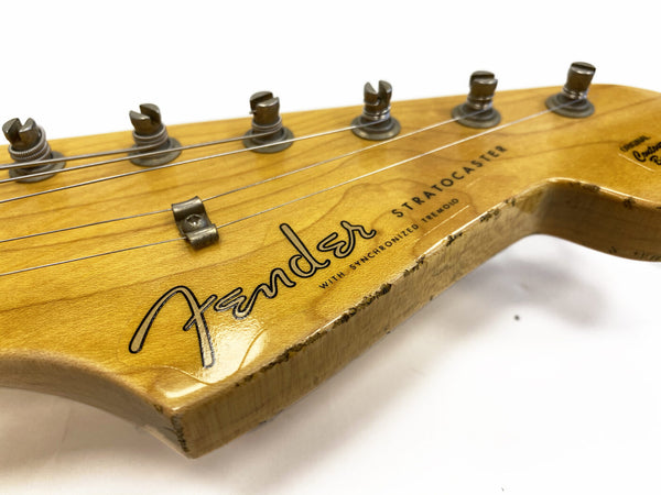 Close-up of vintage Fender Stratocaster guitar headstock with tuning pegs and string tree on natural wood finish