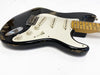 Black vintage-style electric guitar with white pickguard and worn finish showing scratches and paint chips, maple neck with dot inlays, and three single-coil pickups on white background