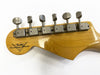 Close-up of vintage Fender Custom Shop guitar headstock with six metal tuning pegs on natural wood finish against white background