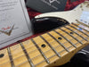 Close-up of Fender electric guitar maple neck and steel frets with certificate of authenticity in background