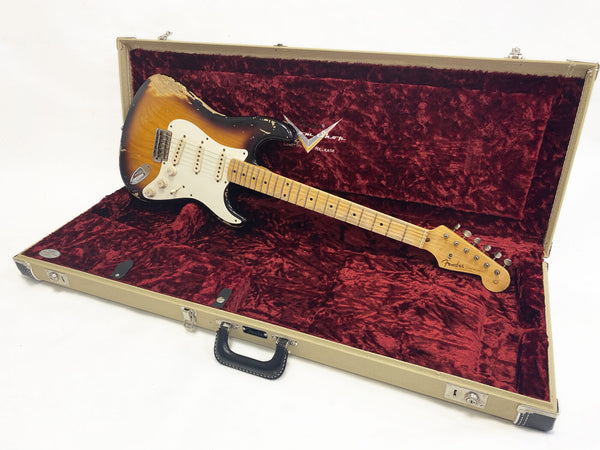 Fender Stratocaster electric guitar with sunburst finish and worn vintage look, displayed inside a beige Fender hard case with red plush interior lining.