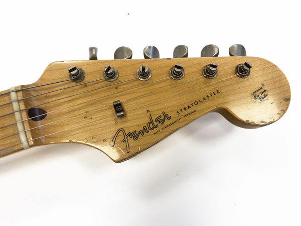 Close-up of vintage Fender Stratocaster guitar headstock with tuning pegs and visible wear marks on natural wood finish