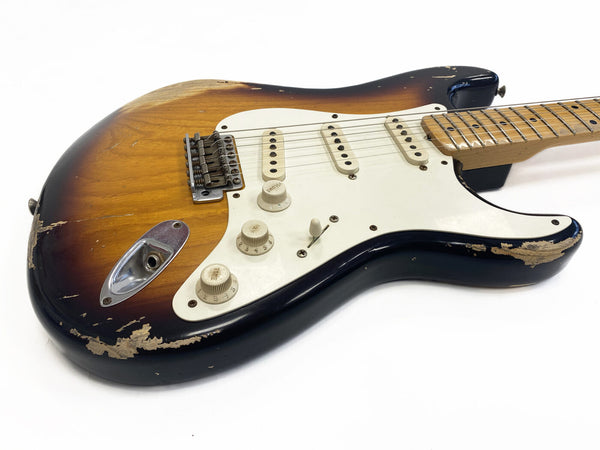 Vintage sunburst electric guitar with white pickguard and three single-coil pickups showing worn and chipped finish on body edges