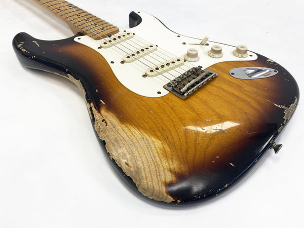 Vintage sunburst electric guitar with worn wood finish and three single-coil pickups on white pickguard