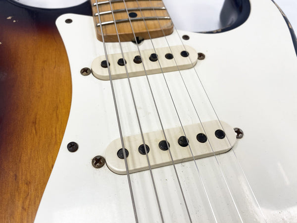 Close-up of vintage electric guitar pickups and strings on sunburst body with white pickguard showing signs of wear and rusted screws