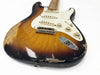 Vintage sunburst electric guitar body with white pickguard and three single-coil pickups showing worn and chipped finish