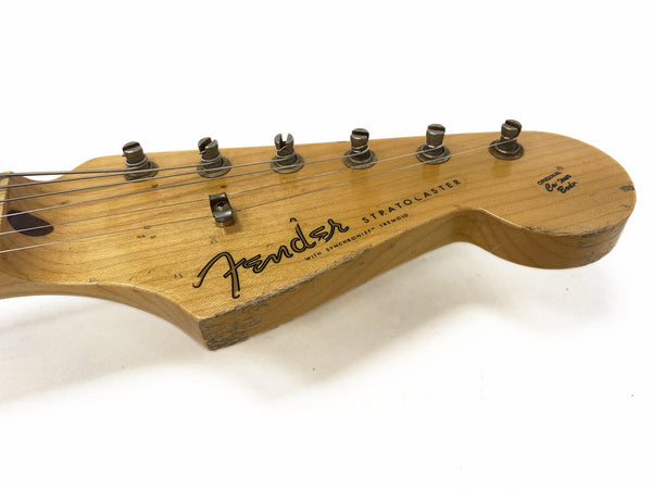 Fender Stratocaster guitar headstock with six tuning pegs, natural wood finish, worn edges, and vintage logo on white background