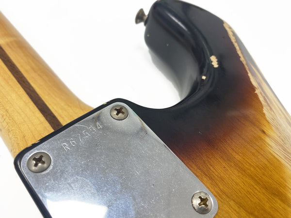 Close-up of vintage sunburst electric guitar neck joint with metal neck plate showing serial number R67554 and maple neck with darker stripe