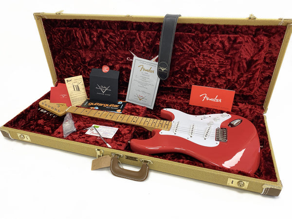 Fender electric guitar in coral finish with maple neck, white pickguard, and vintage tweed hardshell case lined with red plush, including Fender owner's manual, certificate of authenticity, custom care card, tremolo spring guide, and black leather guitar strap
