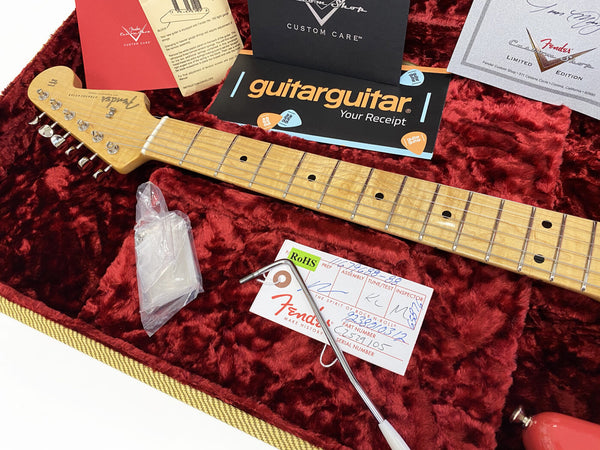 Fender Stratocaster guitar neck with maple fretboard and tuning pegs resting in red plush-lined guitar case, accompanied by Fender Custom Shop papers, guitar maintenance card, tremolo arm, and guitar picks.