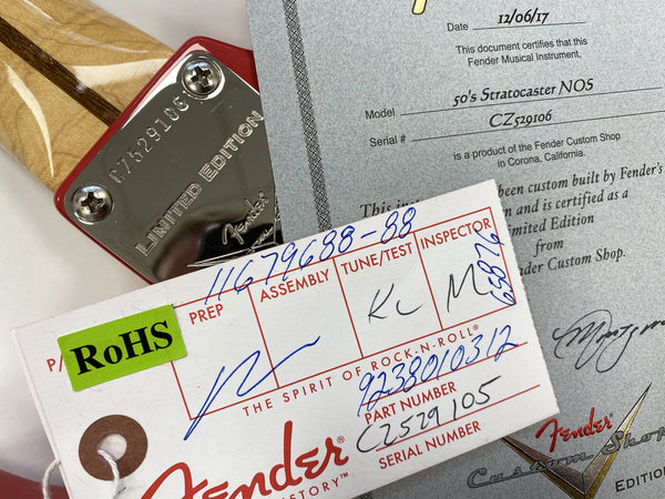 Close-up of Fender Limited Edition guitar neck plate with serial number CZ529106, Fender Custom Shop certificate for 50's Stratocaster NOS dated 12/06/17, and Fender inspection tag with part number C2579105.