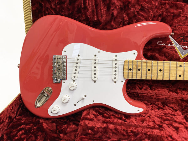 Red Fender Stratocaster electric guitar with white pickguard and maple neck resting in plush red case interior