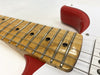 Close-up of electric guitar maple fretboard with metal frets and black dot inlays, red and white guitar body visible.