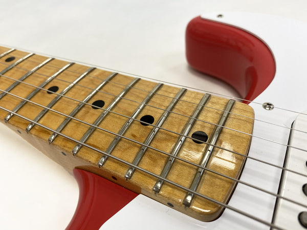 Close-up of electric guitar maple fretboard with metal frets and black dot inlays, red and white guitar body visible.