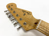 Close-up of natural wood Fender Stratocaster electric guitar headstock with six chrome tuning pegs and strings.
