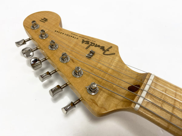Close-up of natural wood Fender Stratocaster electric guitar headstock with six chrome tuning pegs and strings.