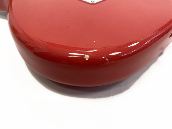 Close-up of red electric guitar body corner showing paint chips and wear on glossy finish