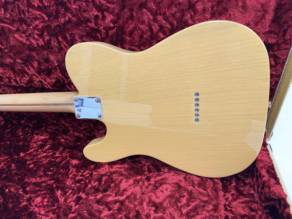 Back view of natural wood finish electric guitar body with six string ferrules, placed inside red plush guitar case