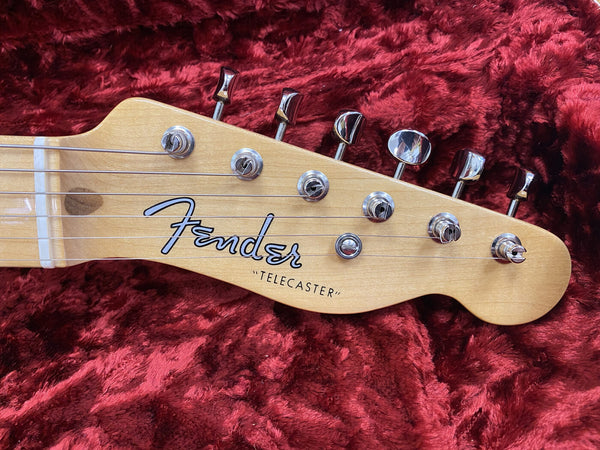 Close-up of Fender Telecaster guitar headstock with tuning pegs and strings on red plush background