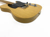 Close-up of natural wood finish electric guitar body with black pickguard and chrome hardware on white background