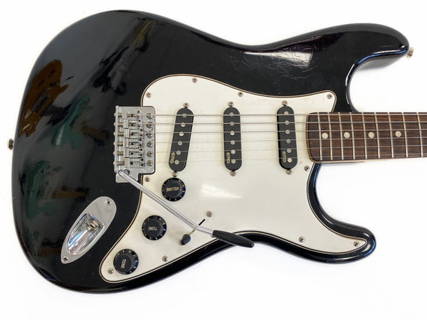 Black electric guitar with white pickguard and three EMG single-coil pickups, vintage-style tremolo bridge, and rosewood fretboard on white background