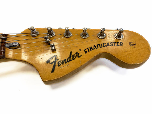 Close-up of vintage Fender Stratocaster guitar headstock with tuning pegs and strings on white background, showing original contour body decal and patent number.