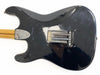 Black electric guitar body back with visible tremolo springs and maple neck with skunk stripe, vintage wear and scratches visible