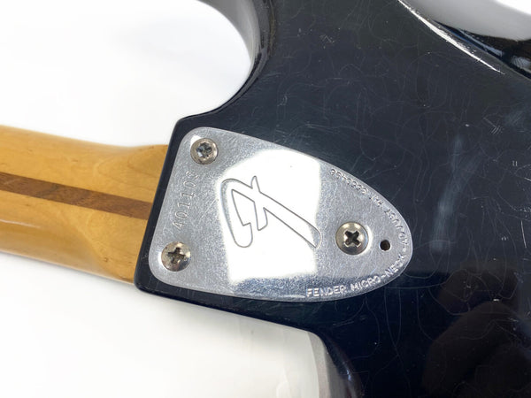 Close-up of Fender Micro Neck-Adjust chrome neck plate on black electric guitar with serial number 401103 and wooden neck with darker stripe.