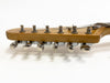 Close-up of vintage guitar headstock with six metal tuning pegs and strings on light wood finish