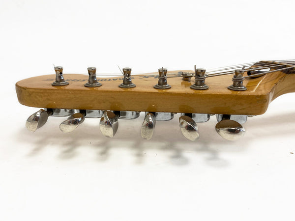 Close-up of vintage guitar headstock with six metal tuning pegs and strings on light wood finish