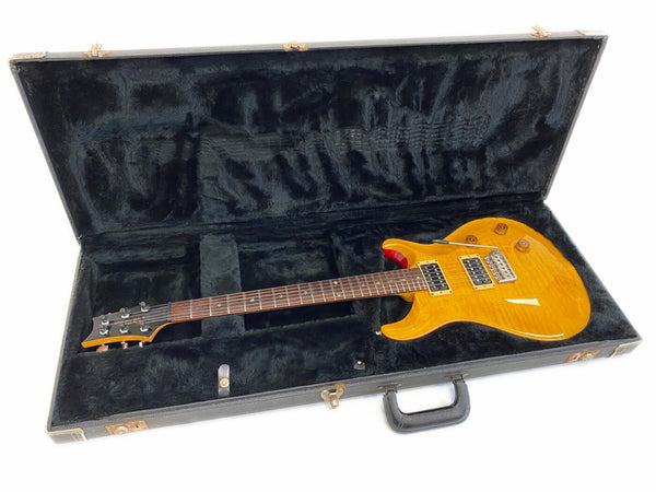 Electric guitar with honey burst finish and dual humbucker pickups inside black plush-lined guitar case