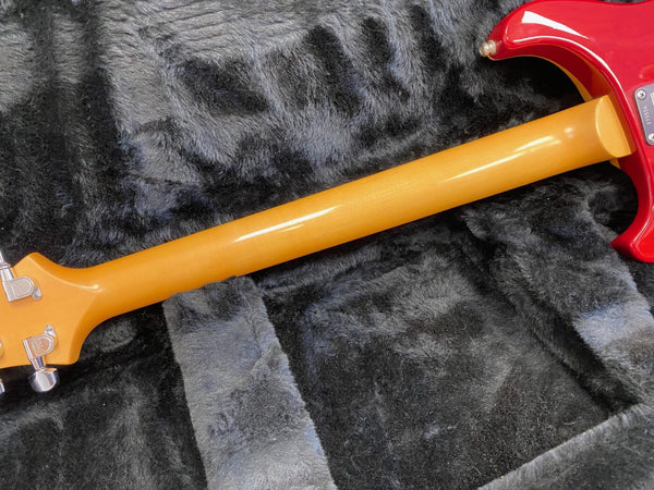 Close-up of red electric guitar neck and back showing maple neck wood and tuners on black plush guitar case interior