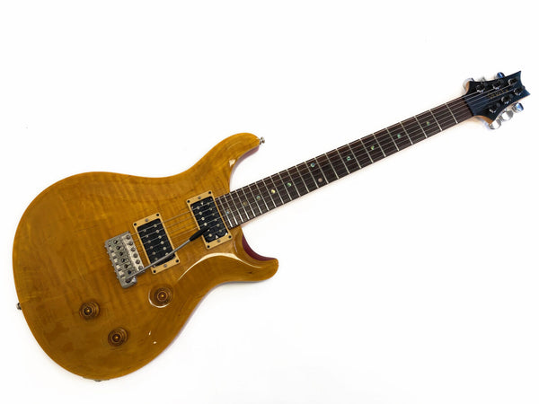 Electric guitar with natural wood finish, dual humbucker pickups, tremolo bridge, and rosewood fretboard on white background