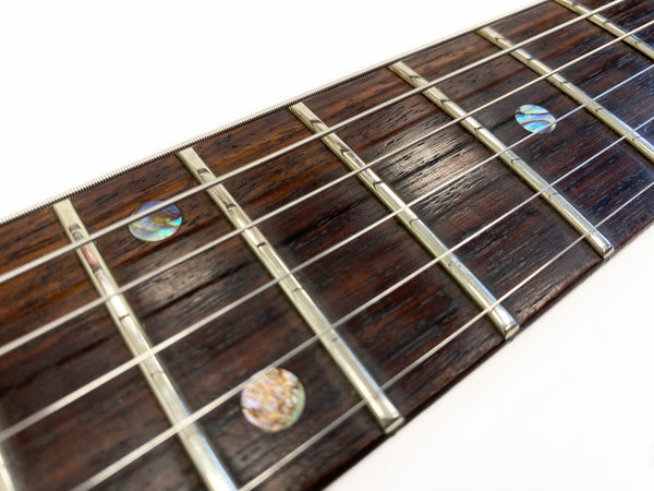 Close-up of dark rosewood guitar fretboard with abalone dot inlays and metal frets on Coffee House Guitars acoustic guitar